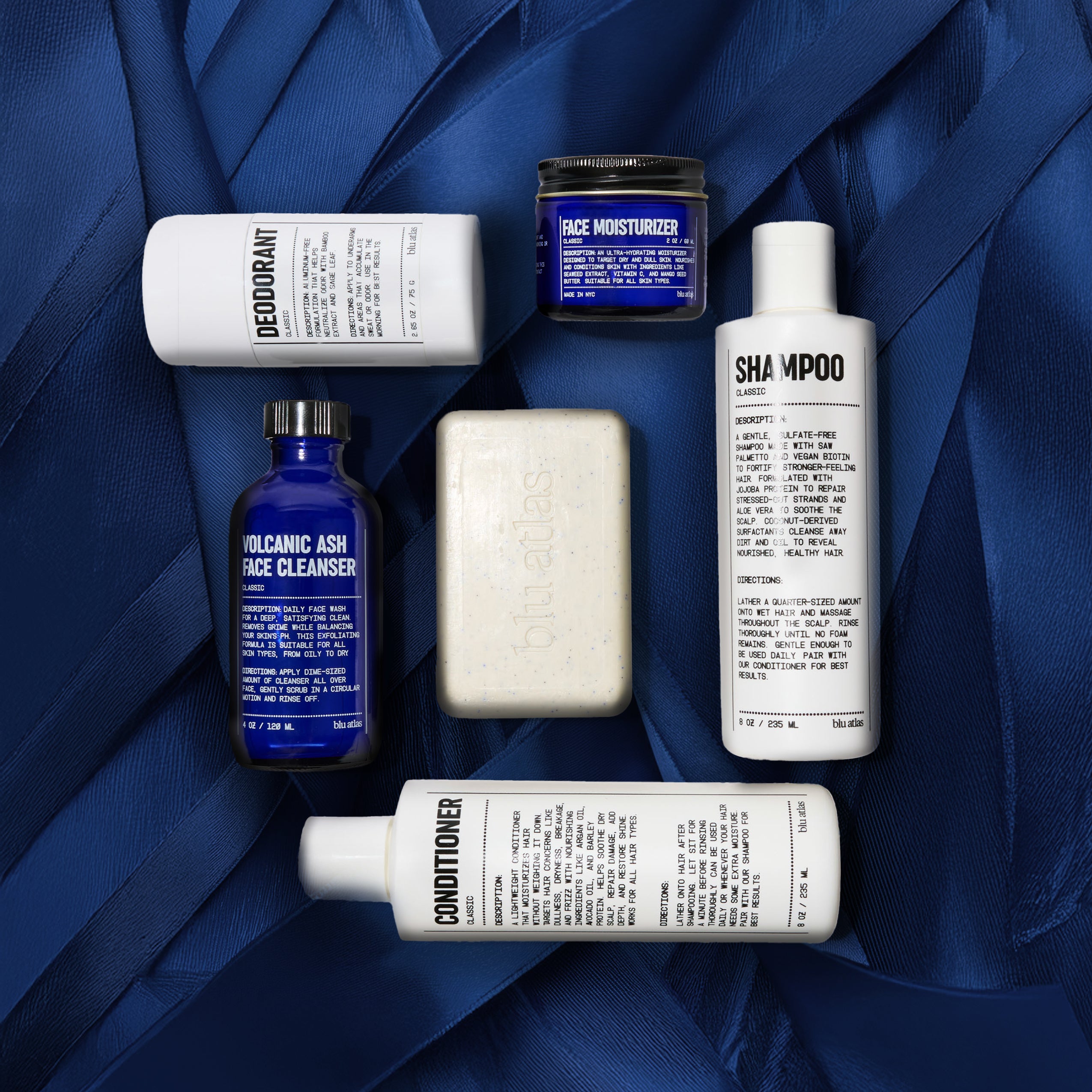 Blu Atlas deodorant, moisturizer, shampoo, soap, face cleanser and conditioner on top of blue ribbon
