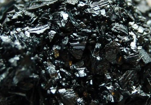 Close-up of shiny, jagged black crystals clustered together.