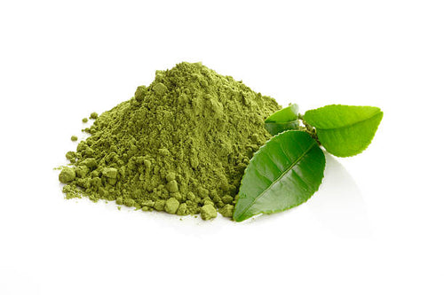A mound of green tea powder is displayed with two fresh green tea leaves on a white background.