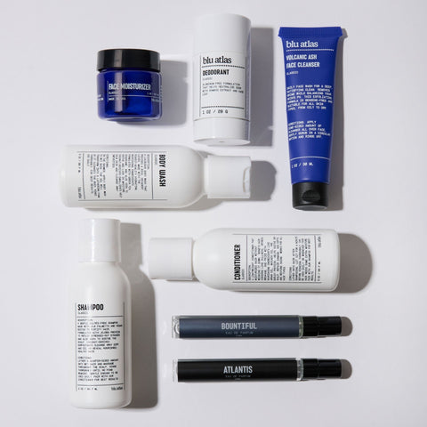 A flat lay of eight Blu Atlas skincare and grooming products, including face moisturizer, deodorant, face cleanser, shampoo, conditioner, and two fragrance vials.