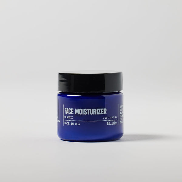 A compact blue jar marked "Travel Sized Hydrating Men's Face Moisturizer" by Blu Atlas, featuring a black lid, stands against a plain background, promising an ultra-hydrating solution for your skincare needs.