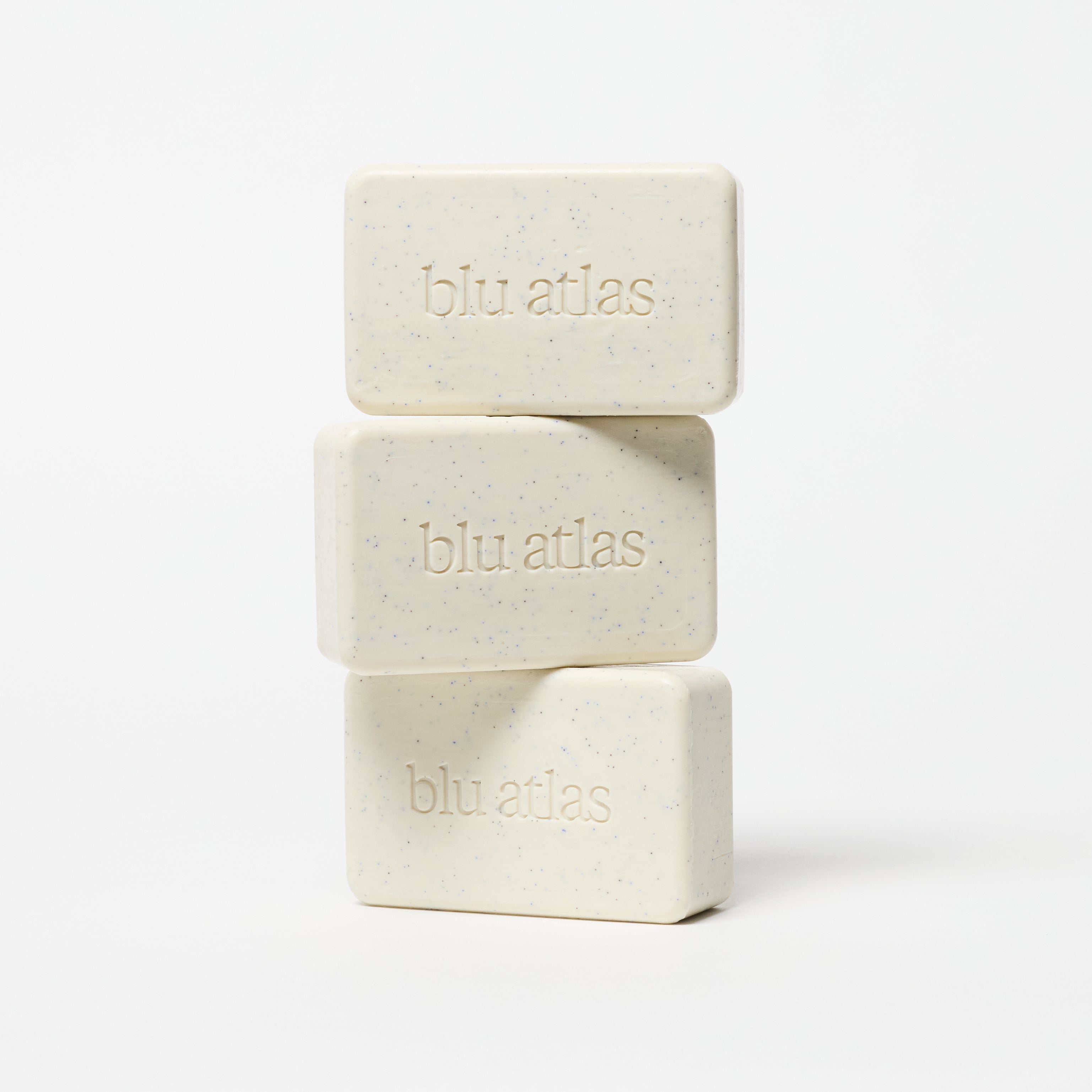 Three stacked bars of Blu Atlas Natural Exfoliating Bar Soap, enriched with jojoba beads, sit against a white background.