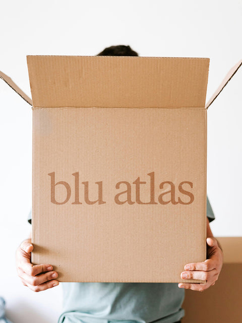 A person holds a box labeled Blu Atlas, containing their LA Wildfire Sponsorship, showcasing support and comfort for the LA Relief Effort with personal care products.