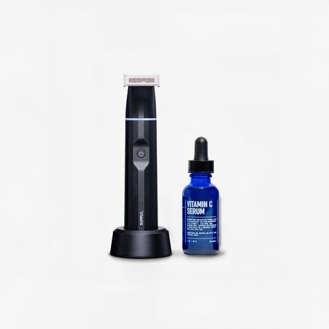 The Trim & Renew Bundle by Blu Atlas features an electric personal trimmer with a charging stand and a blue bottle of Vitamin C Serum with a dropper cap.