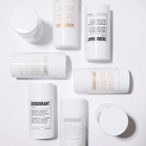 The Deodorant Discovery Set by Blu Atlas features several containers with a subtle tropical fragrance, arranged on a plain surface. Some are lying flat, while others stand upright, each showcasing unique label designs.