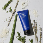 A tube of Blu Atlas Protect & Moisturize Duo rests on a light surface, surrounded by aloe, rosemary, lavender, and flakes. Perfect for natural skincare enthusiasts seeking UVA/UVB protection with water- and sweat-resistant SPF 30.