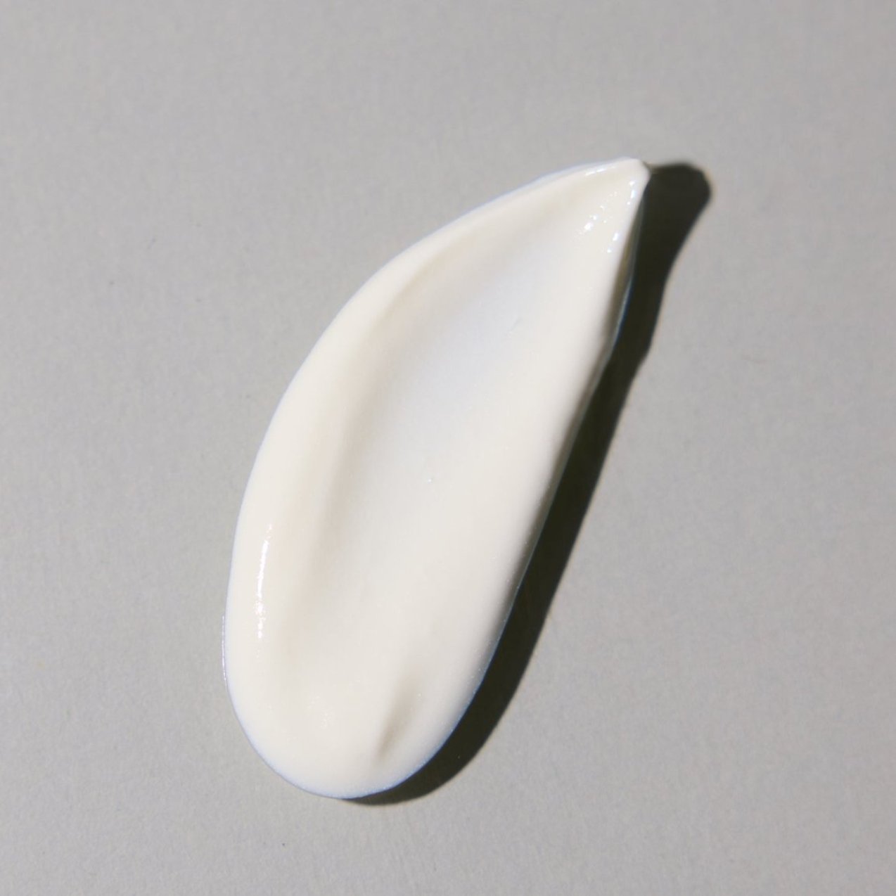 The Protect & Moisturize Duo by Blu Atlas features a dollop of white cream on a gray surface, delivering natural skincare benefits with UVA and UVB protection.