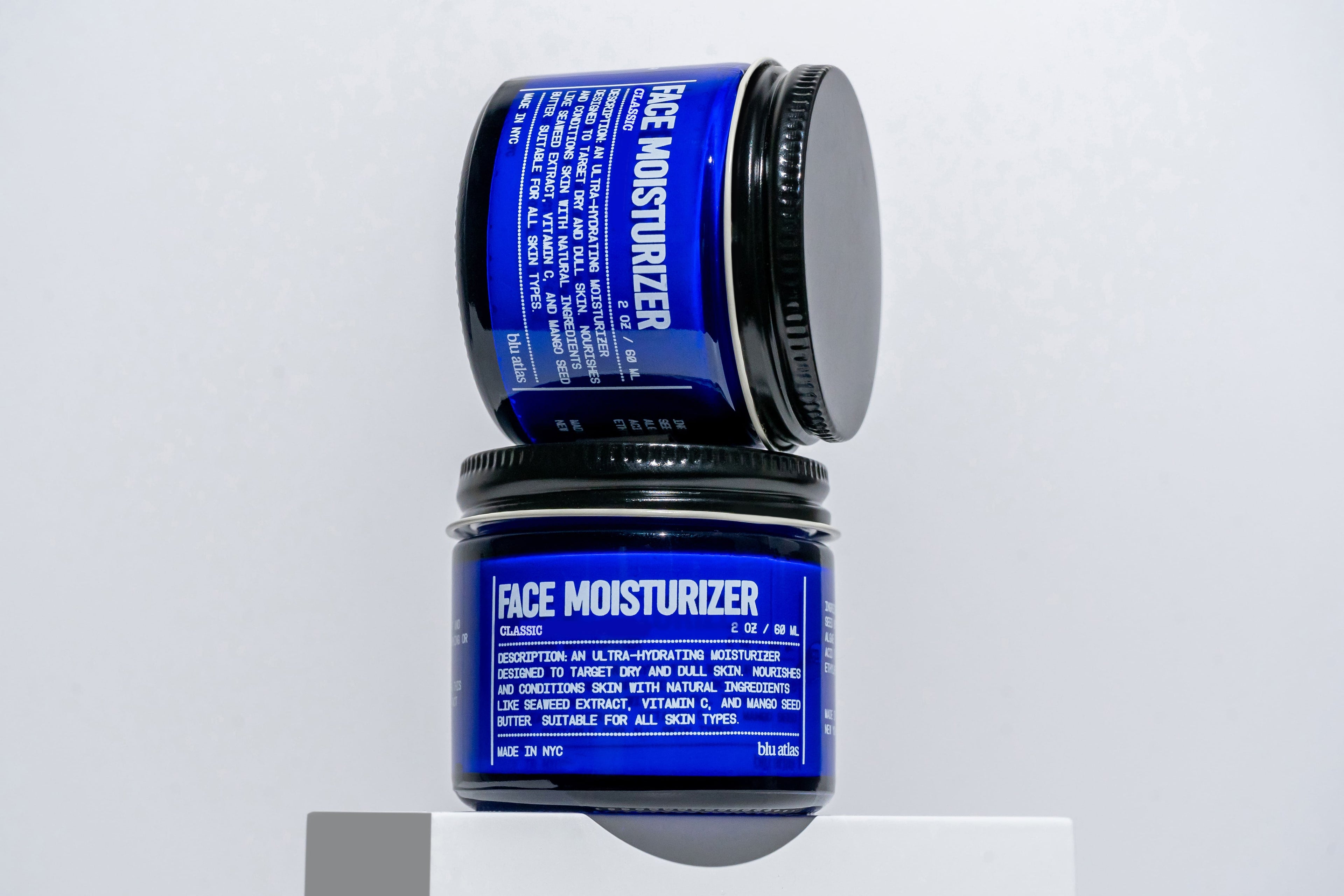 Two jars of face moisturizer with blue labels on a white background