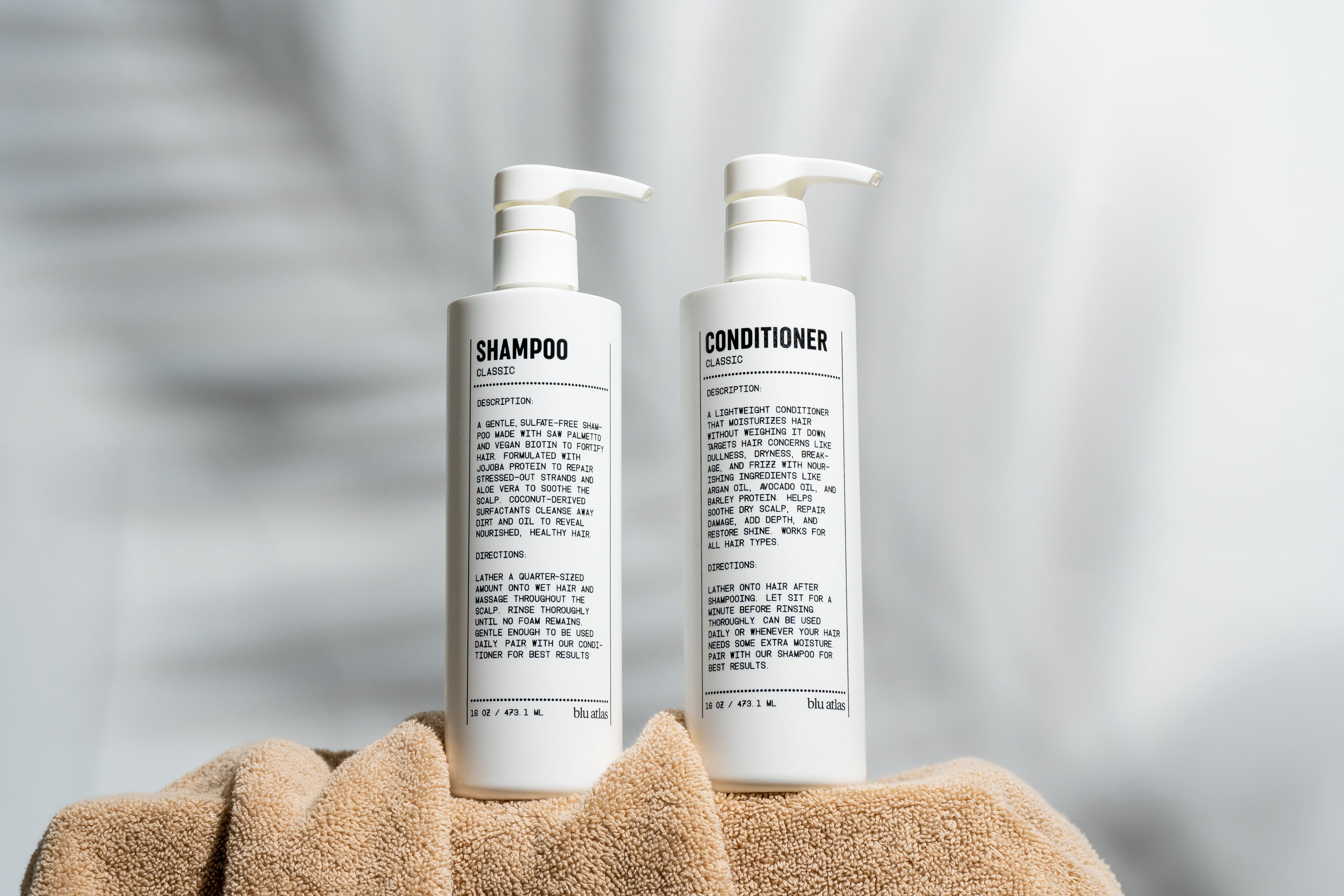 Blu Atlas Shampoo and conditioner bottles on a towel with a neutral background