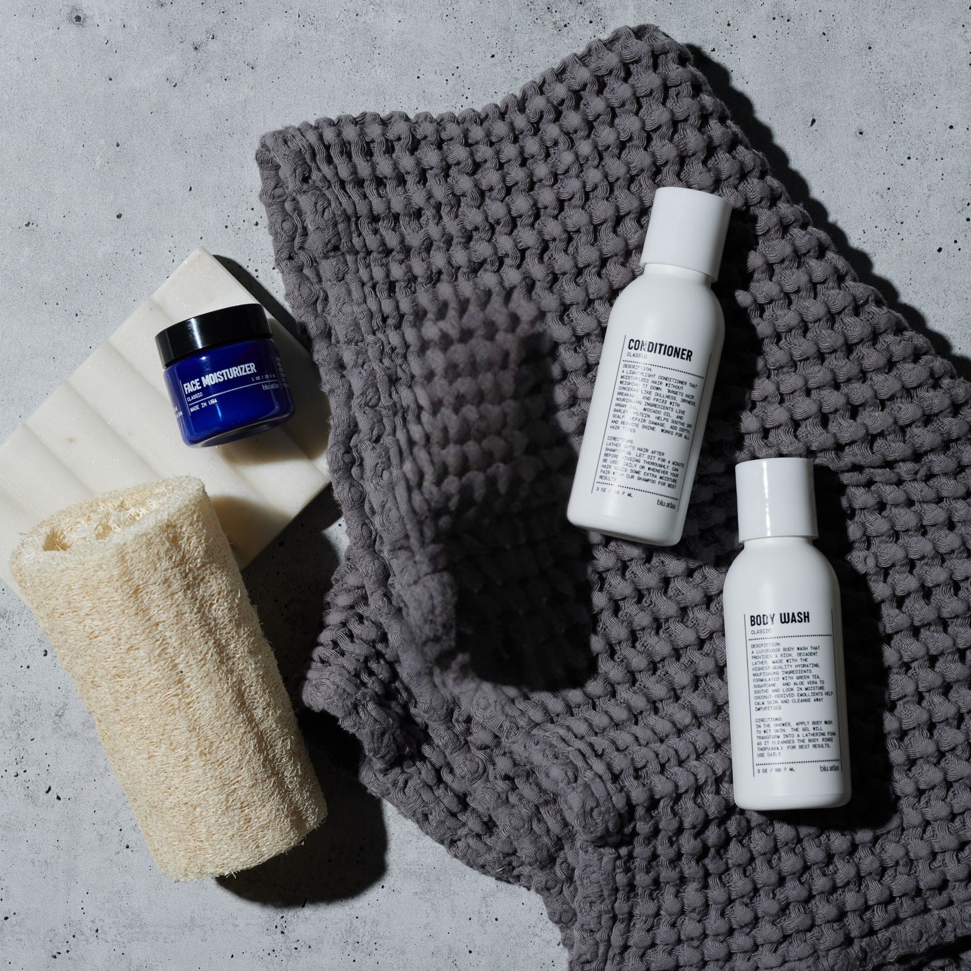 Cosmetic products including a jar, bottles, and a towel on a textured surface