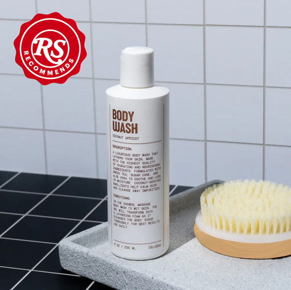 A bottle of Blu Atlas Hydrating Body Wash and a brush gracefully rest on a gray tray against the tiled wall, with an RS Recommends badge in the corner.