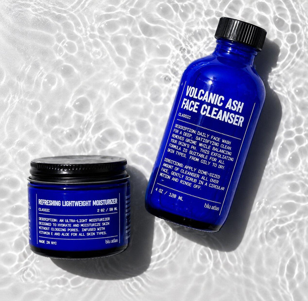 Blu Atlas Face Essentials (Cleanser + Moisturizer) set, featuring blue packaging, is displayed on a textured surface with light reflections—ideal for your daily skincare routine.