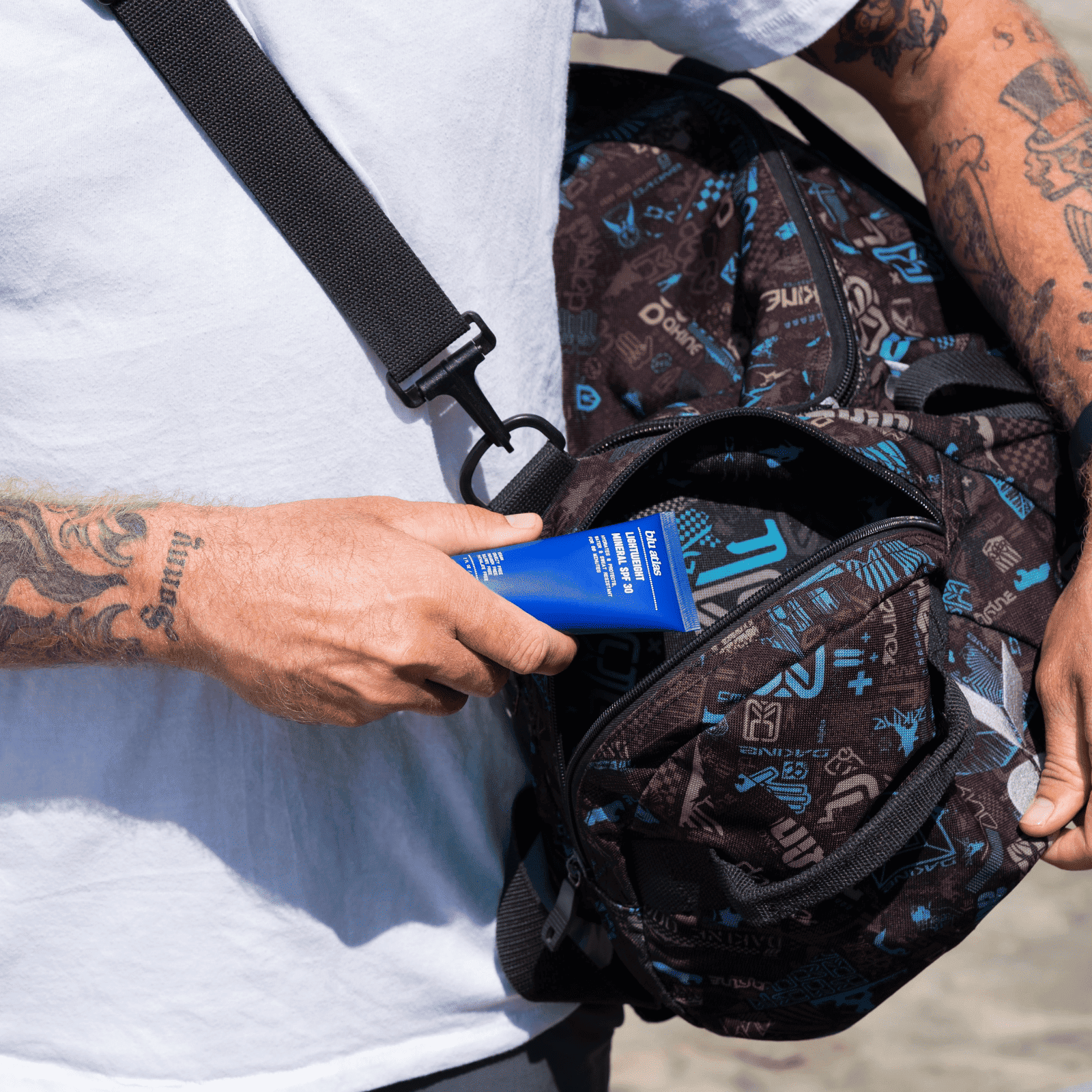 Person holding a blue tube of cream next to a patterned backpack