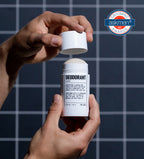 Hands opening a Blu Atlas Add 48-Hour Natural Deodorant against a tiled background, showcasing a Grooming Awards badge in the top right corner.