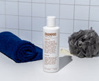 image of Blu Atlas Coconut Apricot Shampoo- coconut apricot on marble counter with sponge and towel 